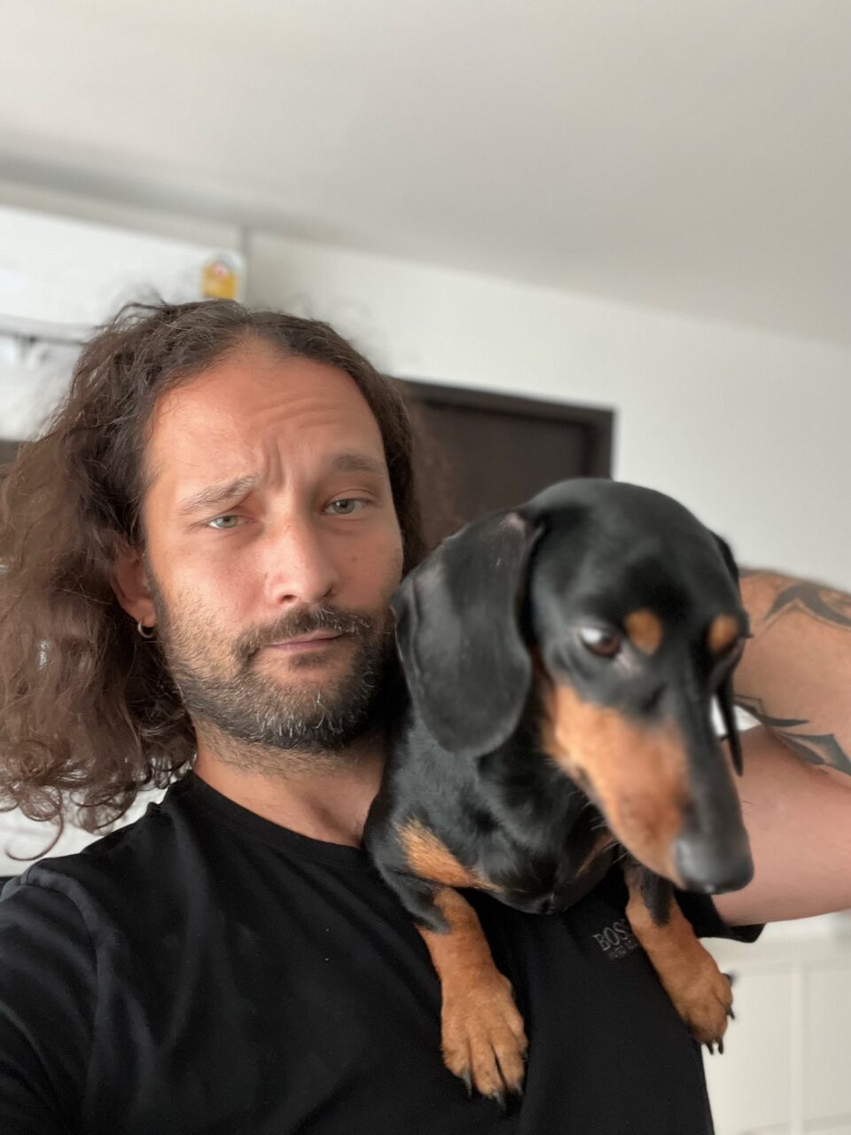 Niko Minadze holding a black-and-tan dachshund at home